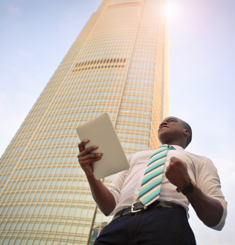 African American Businessman showing emotion/excitement in front of skyscraper.